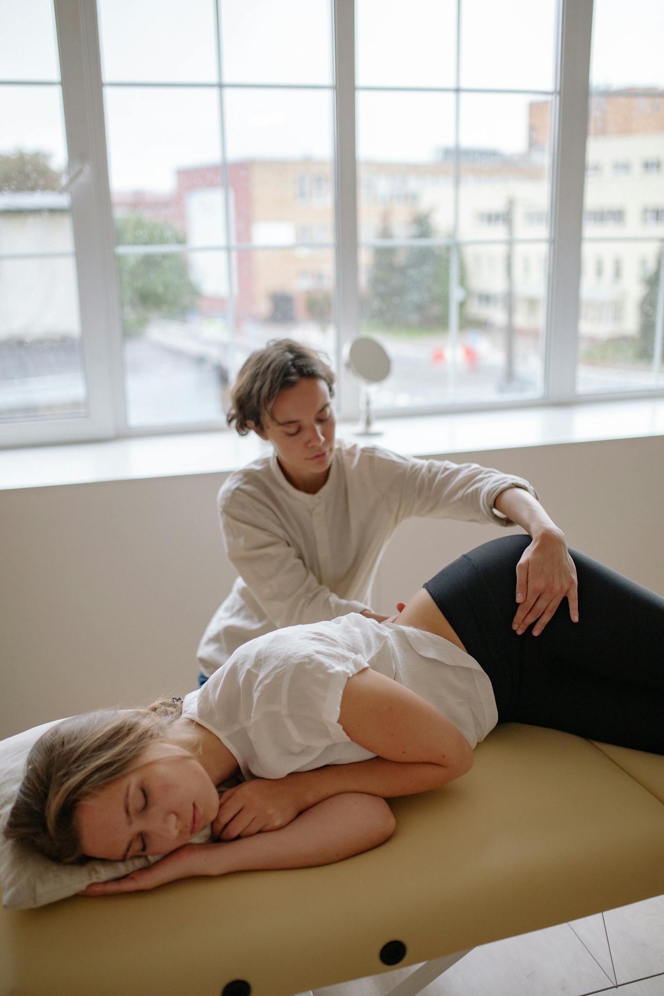 A therapist provides a therapeutic massage to a woman in a modern clinic setting.