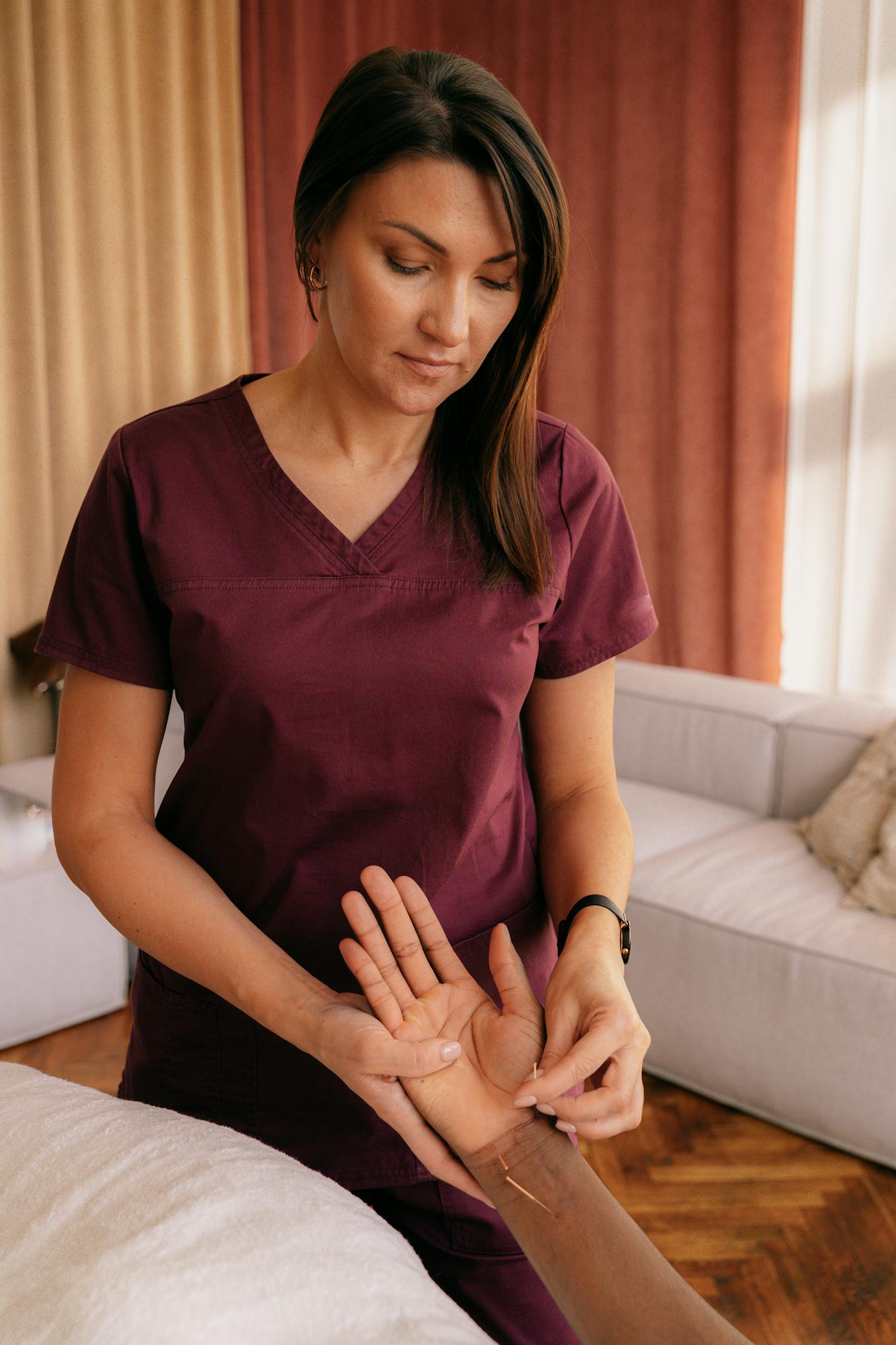 Acupuncturist applies needles during therapy session for health and wellness indoors.